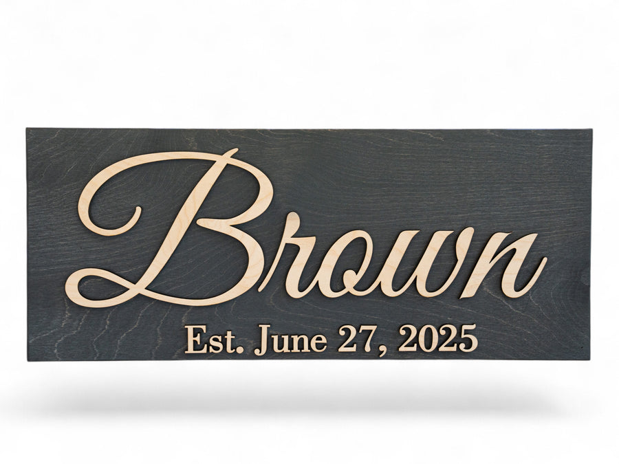 Charcoal-stained wood sign with cream raised script reading Brown, Est. June 27, 2025.
