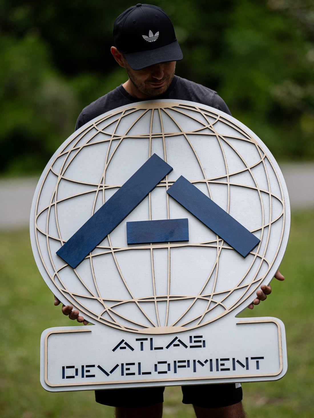 Custom Atlas Development layered wooden business sign made from Baltic Birch plywood with a raised blue logo and globe-style background lines.