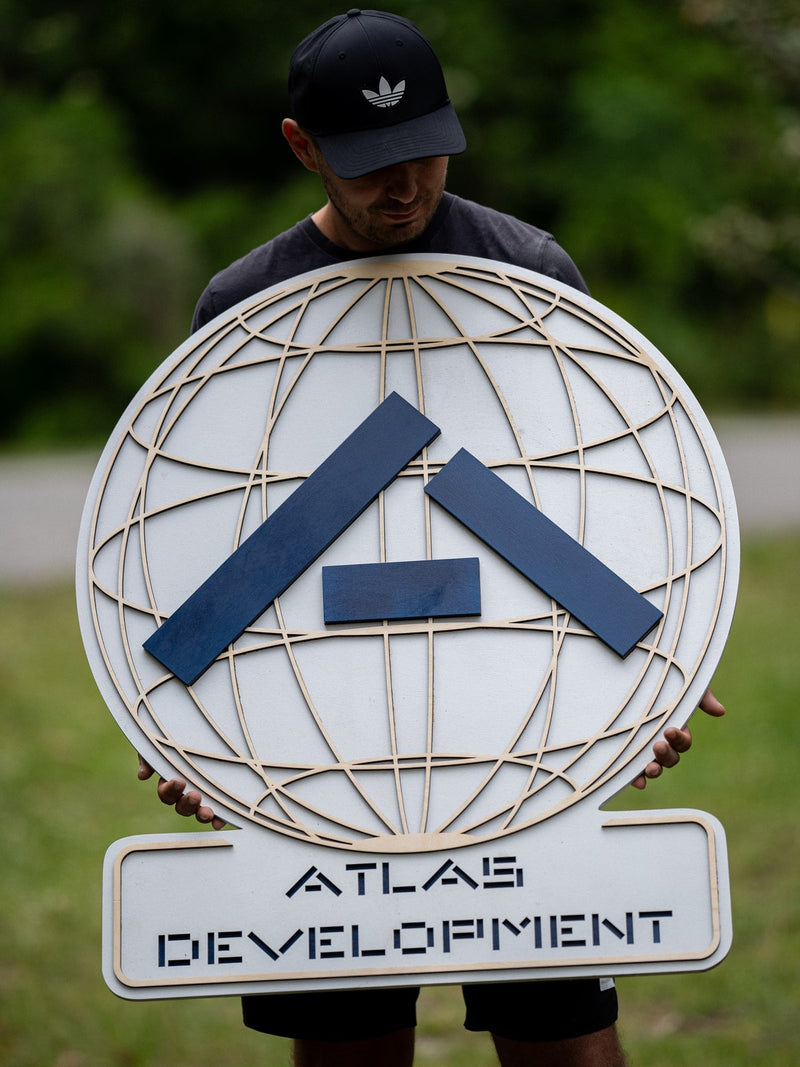 Custom Atlas Development layered wooden business sign made from Baltic Birch plywood with a raised blue logo and globe-style background lines.