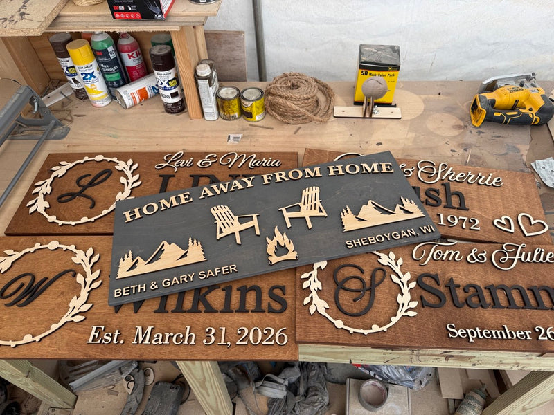 Five custom wooden family name signs on workshop table ready for shipping. Handcrafted personalized signs made in Tampa workshop by WoodHarmonyUS.