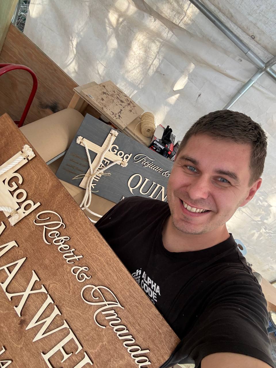 WoodHarmonyUS owner holding handmade unity cross ceremony signs with scripture text God Redeems and Amends for Christian wedding