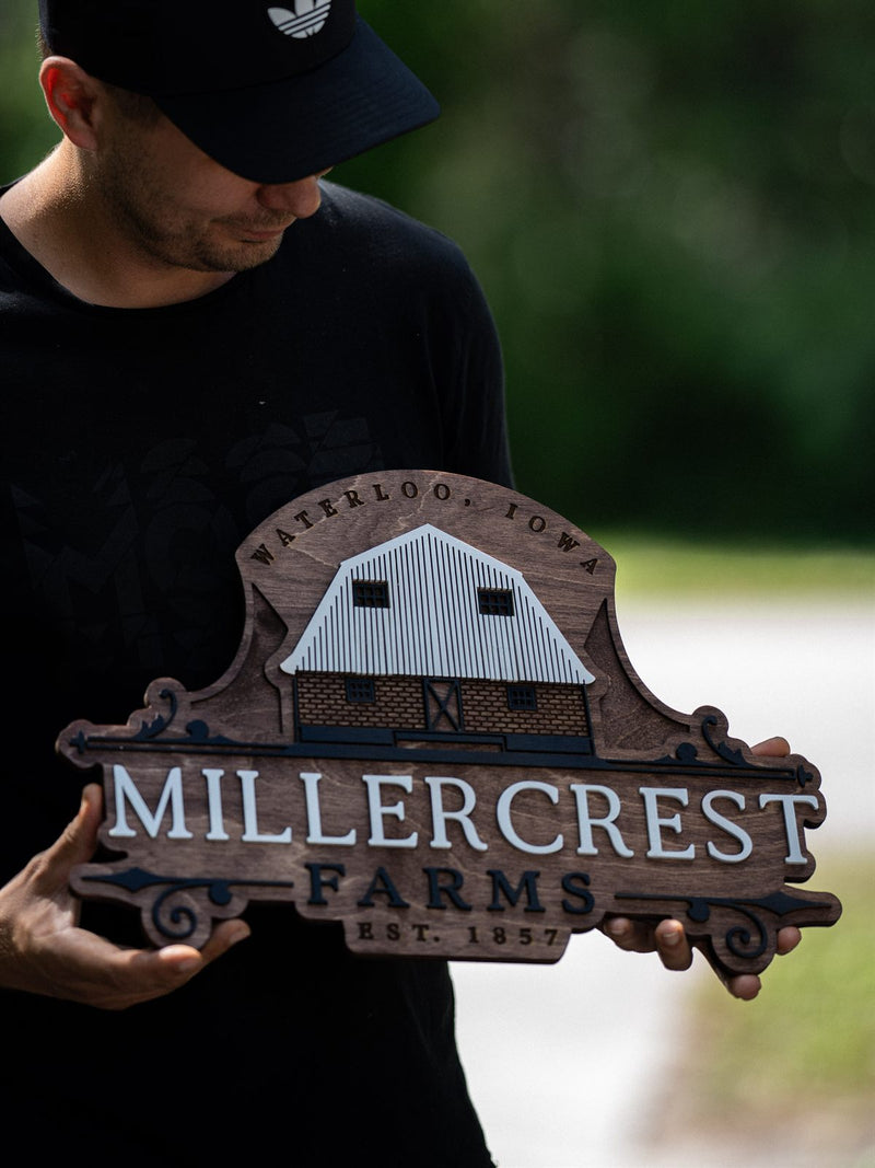 Scroll-shaped dark walnut farm sign for Millercrest Farms, Waterloo Iowa, established 1857, with a layered gambrel barn