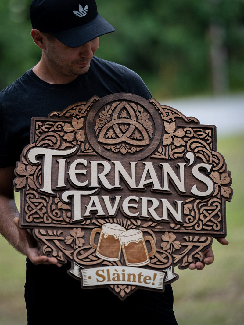 Ornate mid-brown wood pub sign for Tiernan's Tavern with a Celtic triquetra ringed by knotwork, shamrocks and two clinking beer steins