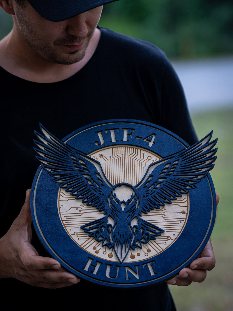 Round navy wood unit crest for JTF-4 Hunt with a many-layered navy eagle over a birch centre engraved with circuit board traces