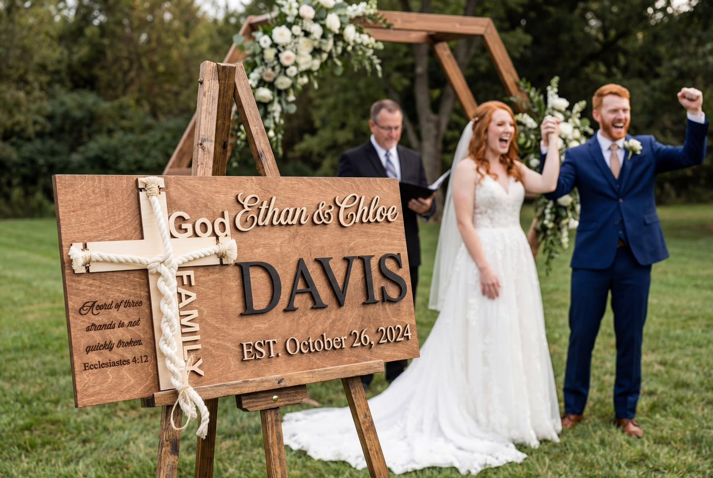 Newlyweds standing next to a personalized Williams family unity cross sign with black letters