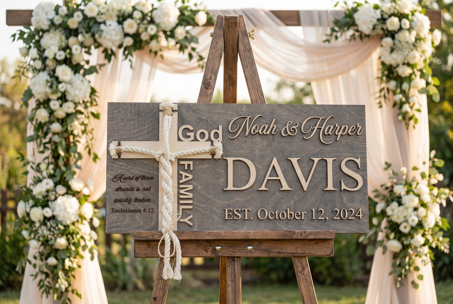 Grey unity cross ceremony sign with the Davis family name, framed by white drapery and flowers