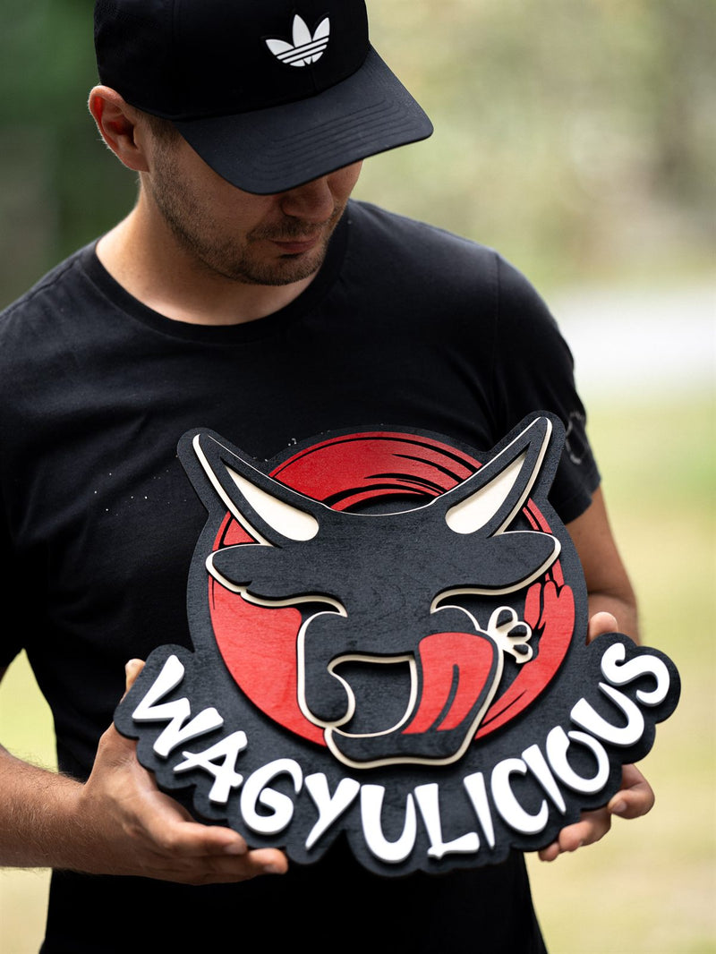 Shaped red and black wood logo sign for Wagyulicious with a layered longhorn bull head with white horns and a pink tongue