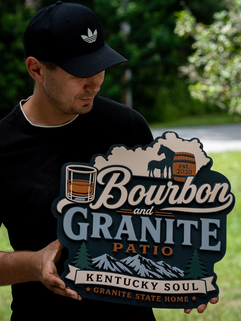 Shaped dark slate wood patio bar sign with a cream tree line, a bourbon glass, two horses and a barrel, reading Bourbon and Granite Patio