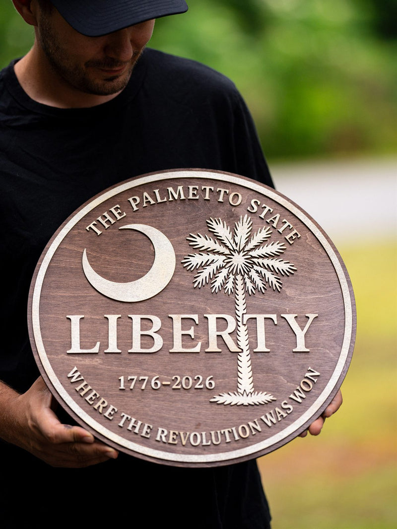 Large round warm brown commemorative wood plaque with a birch crescent moon and palmetto palm, reading The Palmetto State, Liberty, 1776-2026