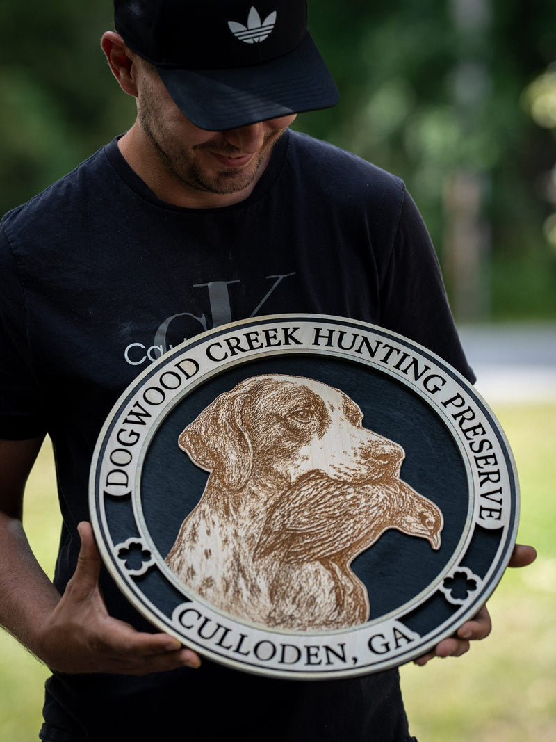 Round cream and slate wood sign for Dogwood Creek Hunting Preserve, Culloden Georgia, with an engraved pointer's head in profile