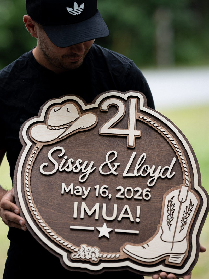 Round walnut wedding sign edged with a birch rope circle, a cowboy hat, script names, the date May 16 2026 and an engraved cowboy boot