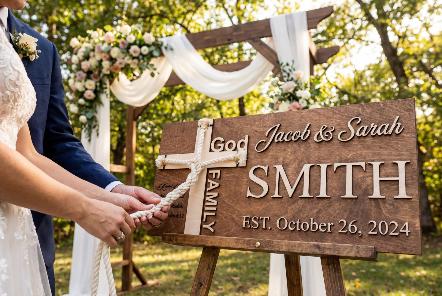 Unity ceremony cross sign in natural wood at a draped wedding arch with white flowers