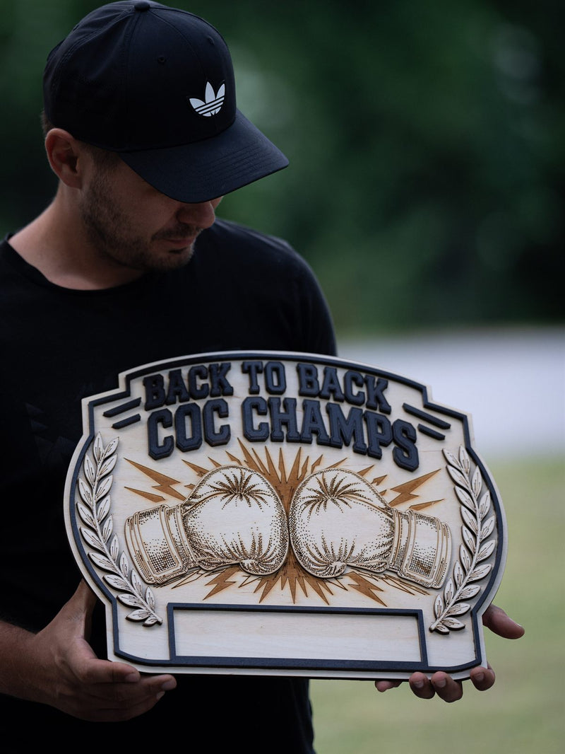 Trophy-shaped pale birch award plaque with engraved boxing gloves in a burst of lightning bolts and laurel branches