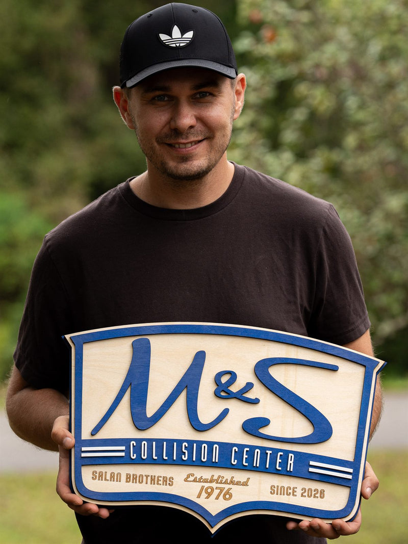 Shield-shaped blue and birch wood shop sign for M and S Collision Center, Salan Brothers, established 1976