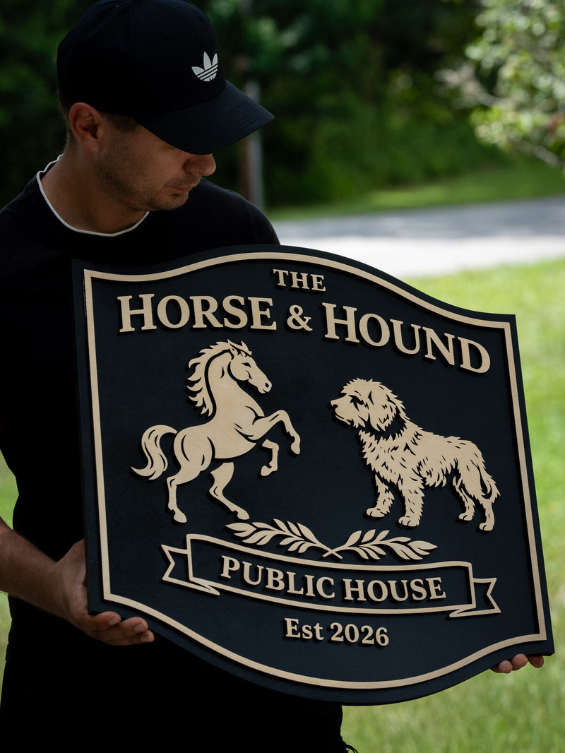 Rounded-square near-black wood pub sign with a cream border, a rearing horse facing a shaggy hound, reading The Horse and Hound Public House