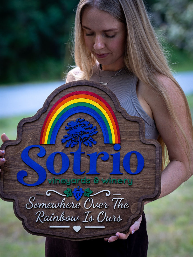 Dark walnut wood winery sign for Sotrio Vineyards and Winery with rainbow bars, a blue oak tree and a grape cluster